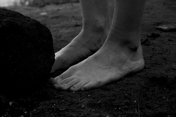 Bare feet standing firmly on a natural wooden surface.