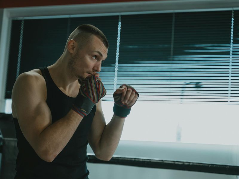 Man in a focused stance in a minimalist, dark training space.
